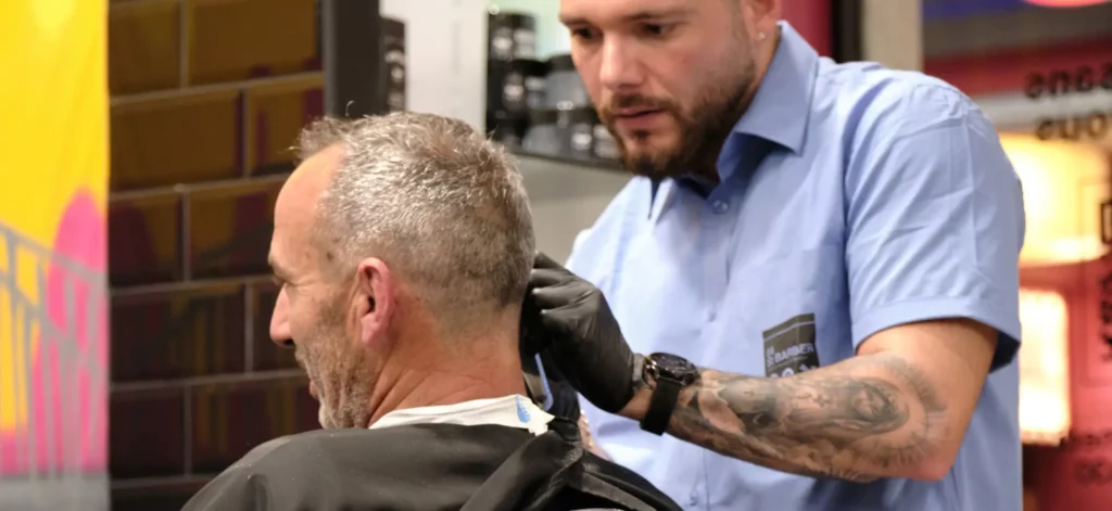 Barbier en action chez 04 ST BARBER Béziers, réalisant un rasage sur un client