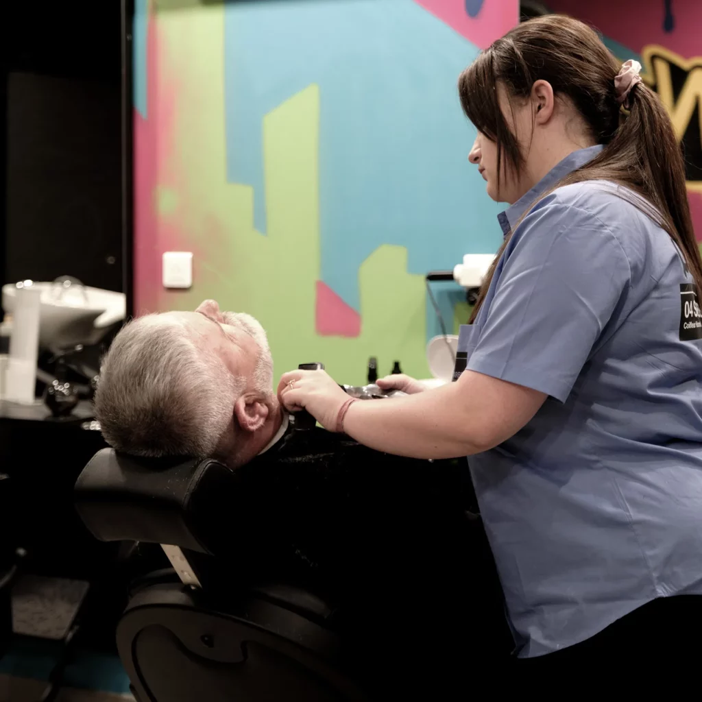 Barbier réalisant une coupe sur client allongé chez 04 St BARBER Béziers