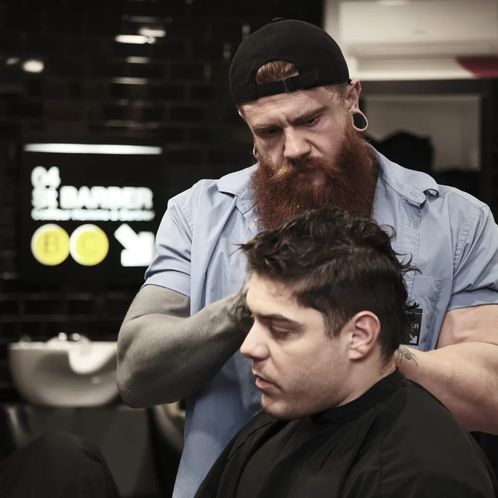 Barbier en train de réaliser une coupe de cheveux stylisée sur un client.